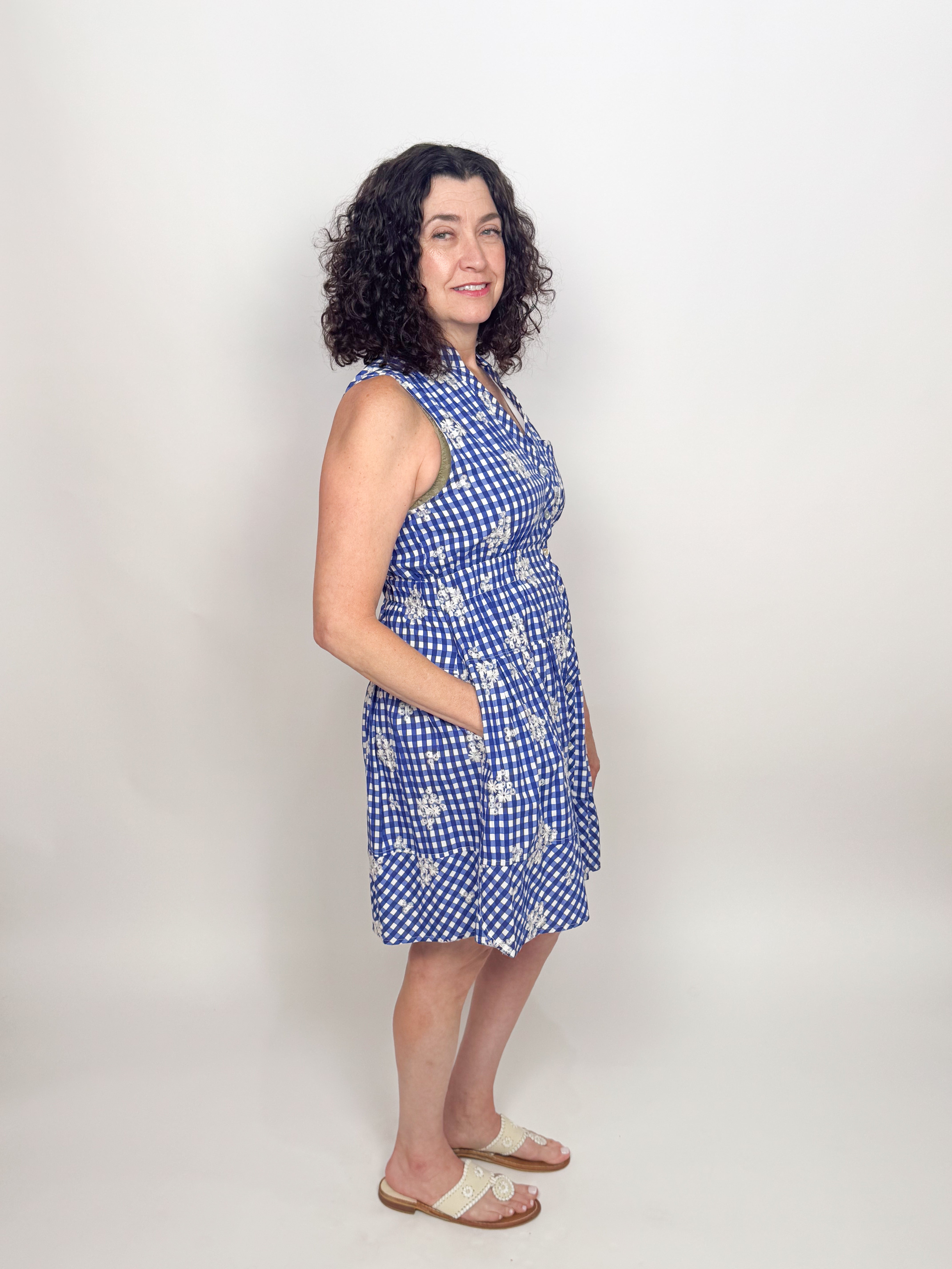 Woman wearing a blue checkered dress with white floral patterns on a plain background
